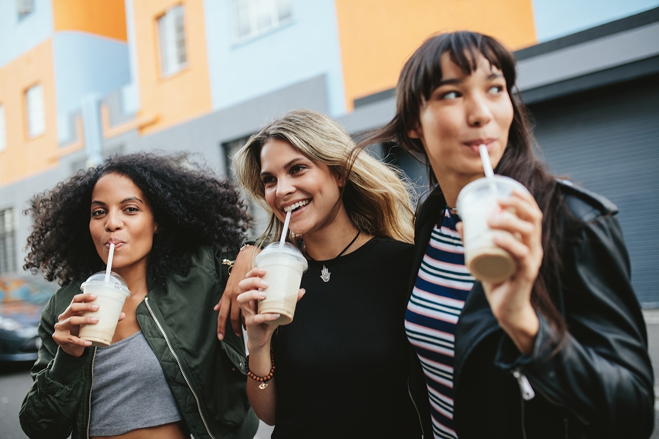 3 women drinking iced coffee on the street