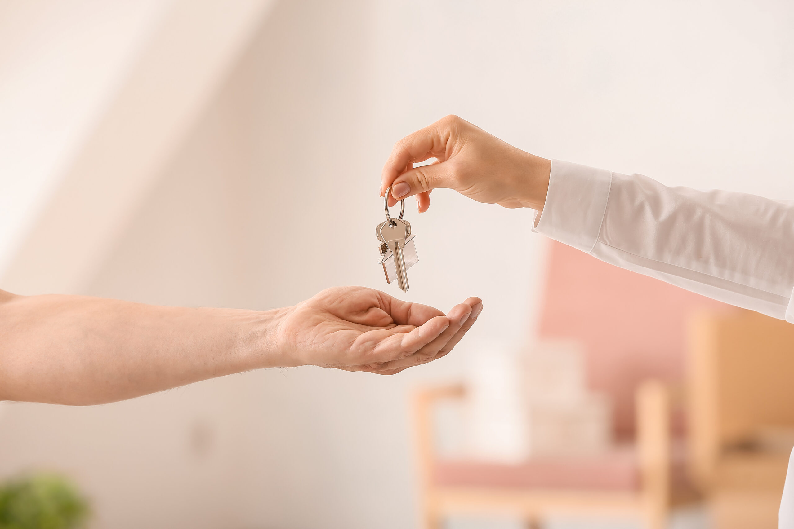 Real estate agent giving keys from house to new owner indoors Real estate agent giving keys from house to new owner indoors