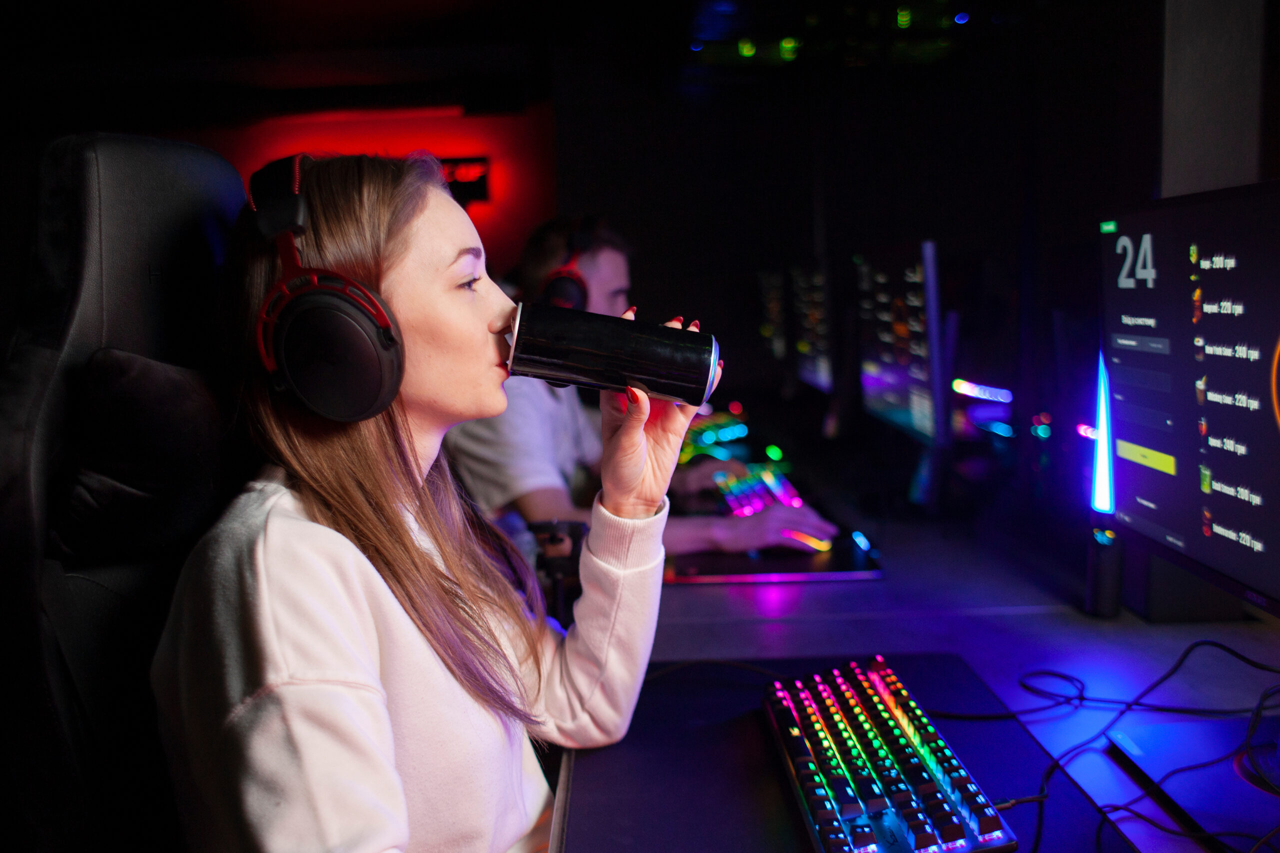 girl gamer sits at a computer and drinks an energy drink, a woman plays in a computer club at night and holds a drink girl gamer sits at a computer and drinks an energy drink, a woman plays in a computer club at night and holds a drink