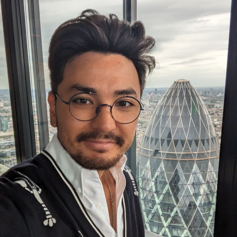 man with glasses taking a picture infront of a window