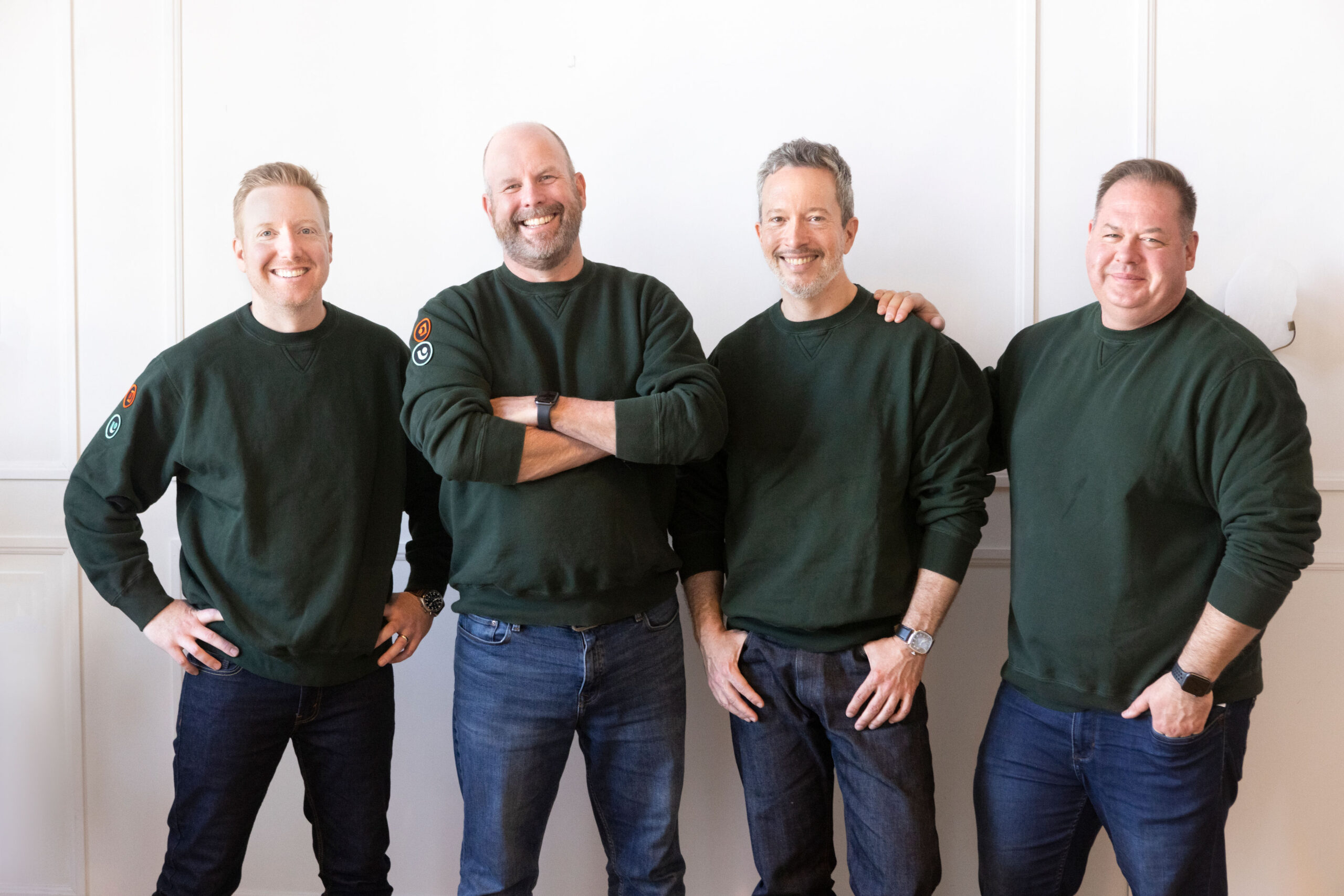 4 men standing in green sweatshirts